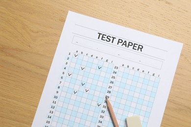 Photo of Answer sheet, eraser and pencil on wooden table, flat lay. Student passing exam