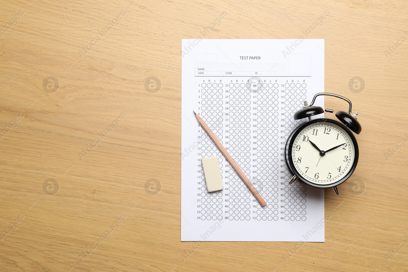 Student passing exam. Answer sheet, eraser, pencil and alarm clock on wooden table, flat lay. Space for text Photo of Student passing exam. Answer sheet, eraser, pencil and alarm clock on wooden table, flat lay. Space for text