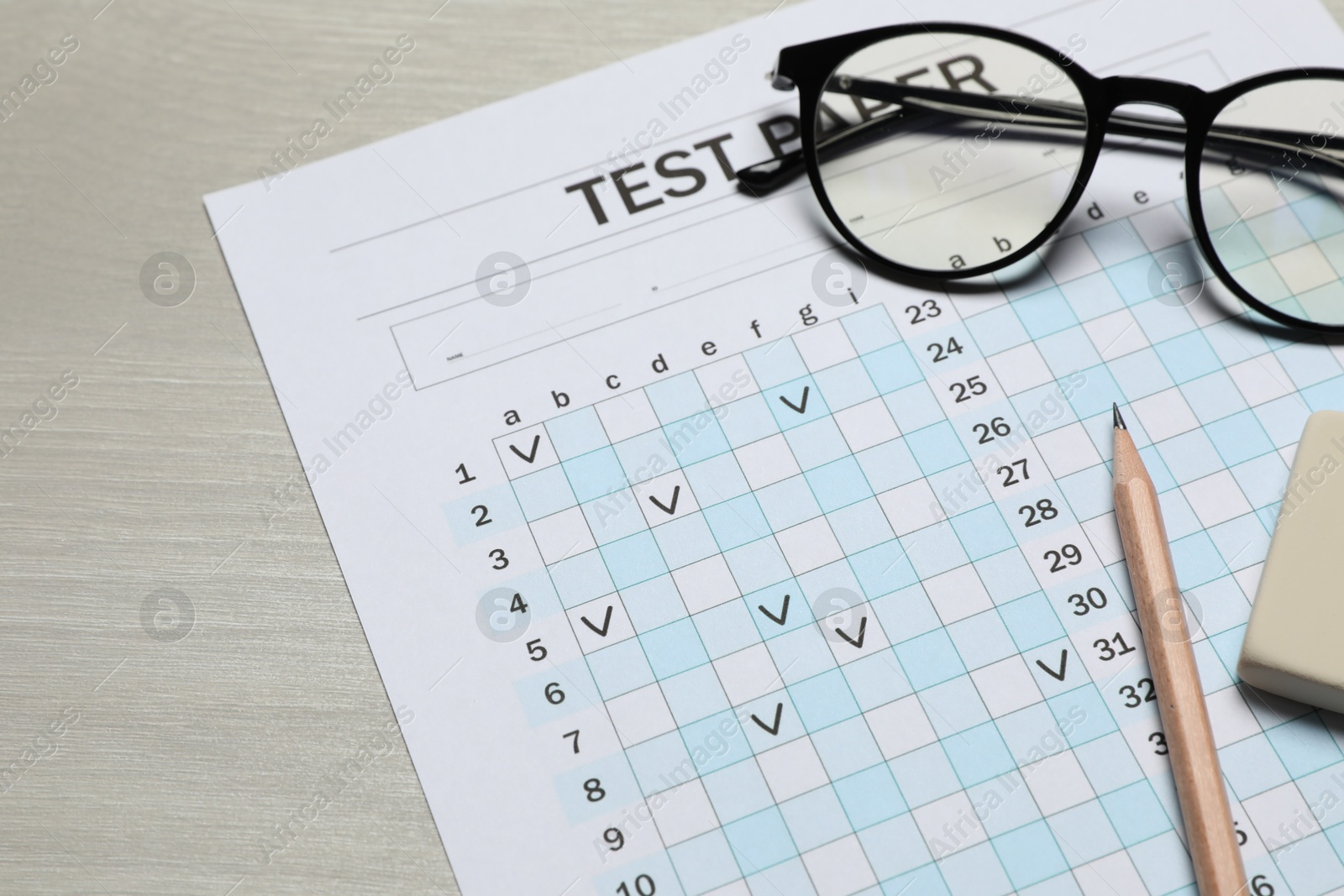 Answer sheet, eraser, pencil and glasses on wooden table, closeup. Student passing exam Photo of Answer sheet, eraser, pencil and glasses on wooden table, closeup. Student passing exam