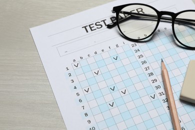 Photo of Answer sheet, eraser, pencil and glasses on wooden table, closeup. Student passing exam
