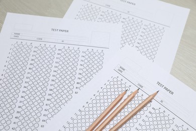 Photo of Answer sheets and pencils on wooden table, closeup. Student passing exam