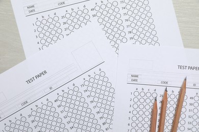 Photo of Answer sheets and pencils on wooden table, flat lay. Student passing exam