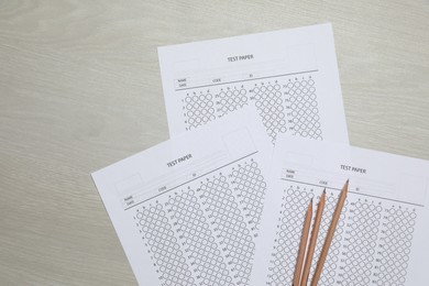 Photo of Answer sheets and pencils on wooden table, flat lay. Student passing exam