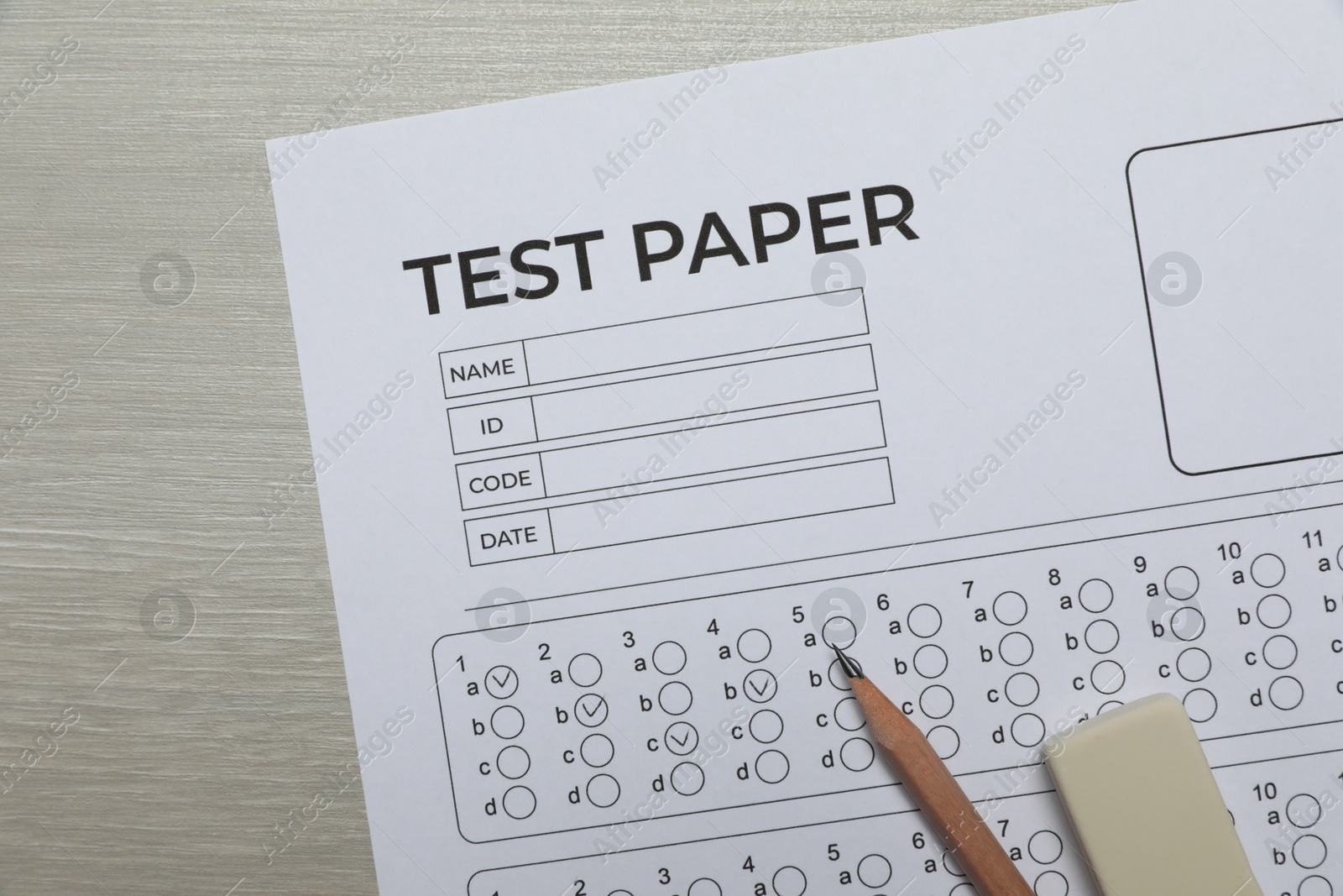 Answer sheet, eraser and pencil on wooden table, flat lay. Student passing exam Photo of Answer sheet, eraser and pencil on wooden table, flat lay. Student passing exam