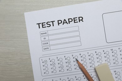 Photo of Answer sheet, eraser and pencil on wooden table, flat lay. Student passing exam