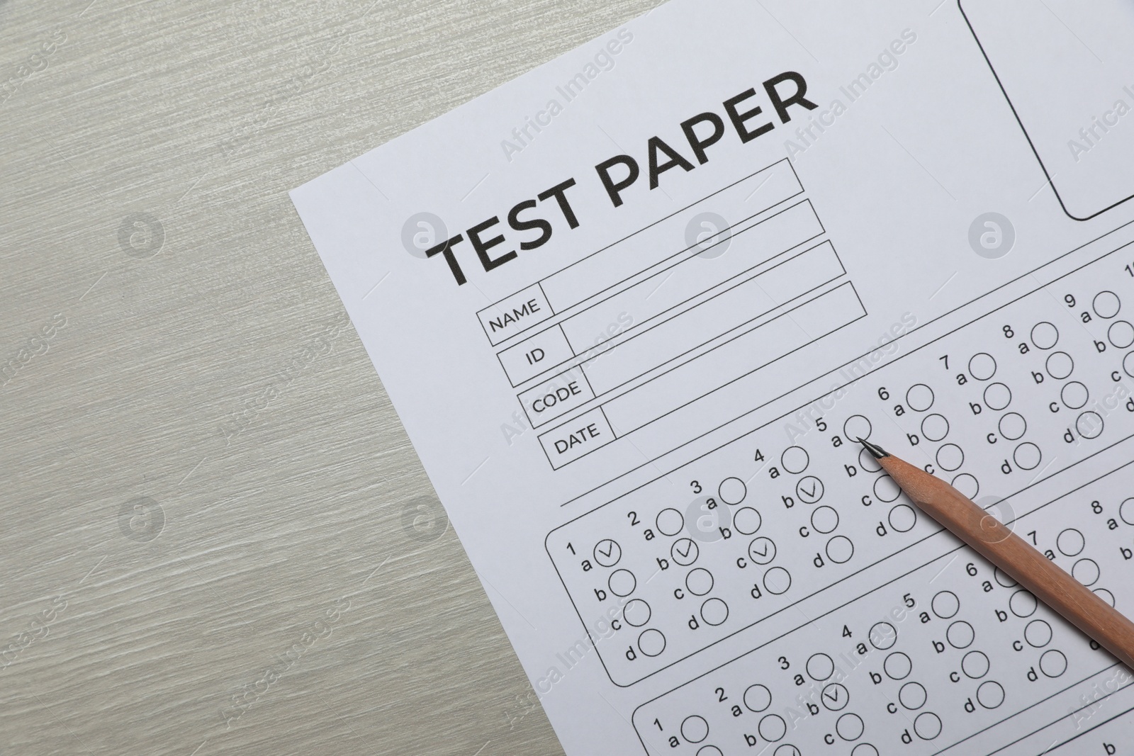 Answer sheet and pencil on wooden table, flat lay. Student passing exam Photo of Answer sheet and pencil on wooden table, flat lay. Student passing exam
