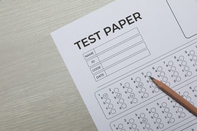 Photo of Answer sheet and pencil on wooden table, flat lay. Student passing exam