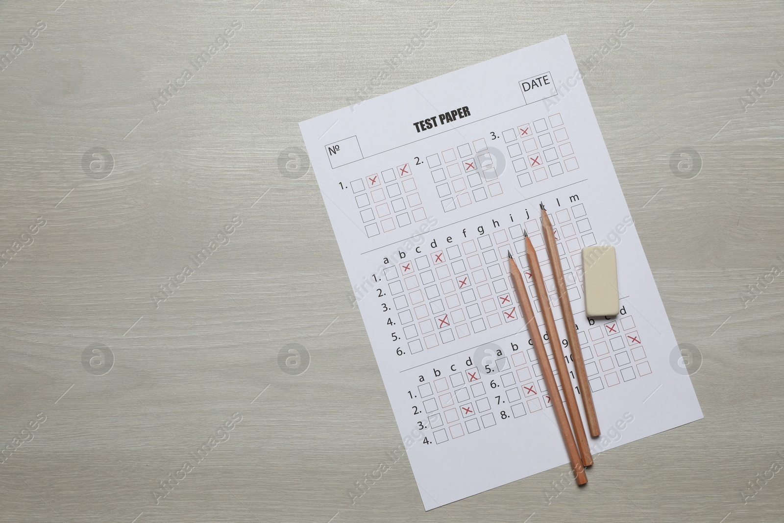Student passing exam. Answer sheet, pencils and eraser on wooden table, flat lay. Space for text Photo of Student passing exam. Answer sheet, pencils and eraser on wooden table, flat lay. Space for text