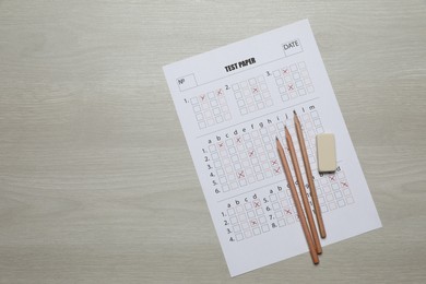 Photo of Student passing exam. Answer sheet, pencils and eraser on wooden table, flat lay. Space for text