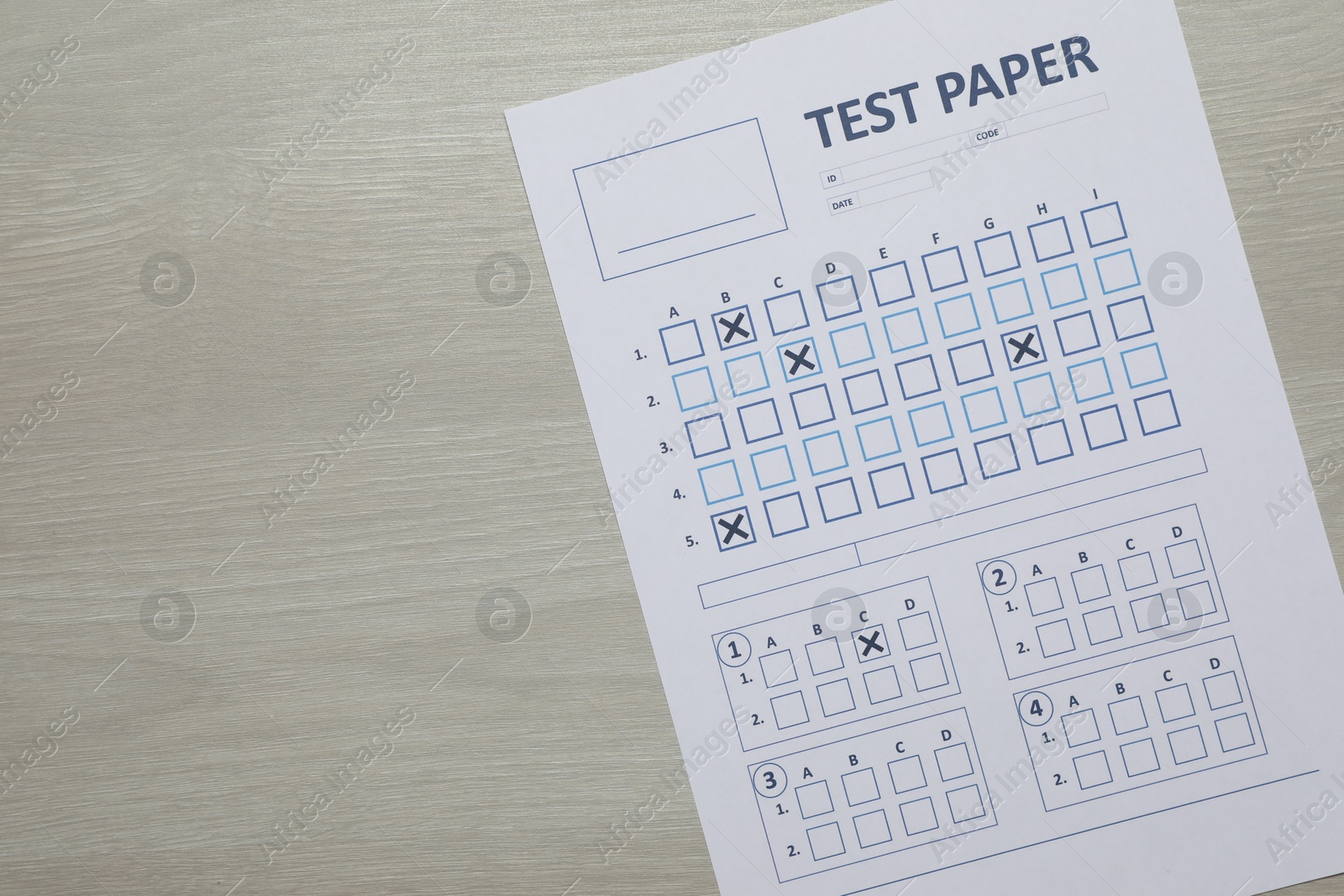 Student passing exam. Answer sheet on wooden table, top view. Space for text Photo of Student passing exam. Answer sheet on wooden table, top view. Space for text