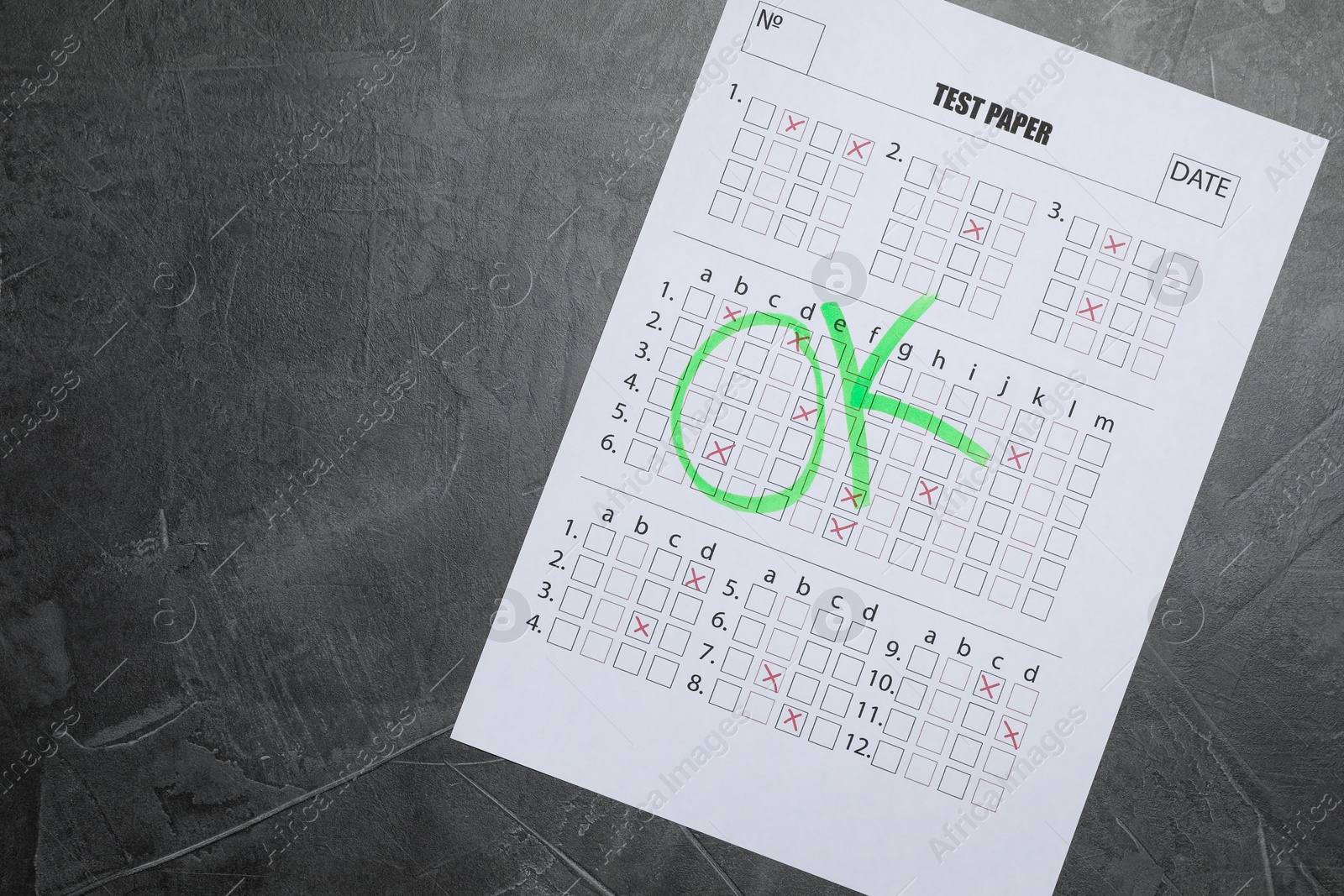 Student passing exam. Answer sheet with word Ok on gray textured table, top view. Space for text Photo of Student passing exam. Answer sheet with word Ok on gray textured table, top view. Space for text