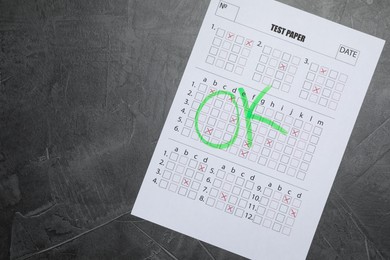 Photo of Student passing exam. Answer sheet with word Ok on gray textured table, top view. Space for text