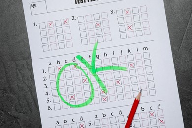 Photo of Answer sheet with word Ok and pencil on gray textured table, top view. Student passing exam