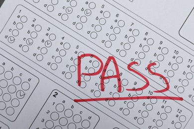 Photo of Word Pass written with red marker on answer sheet, top view. Student passing exam