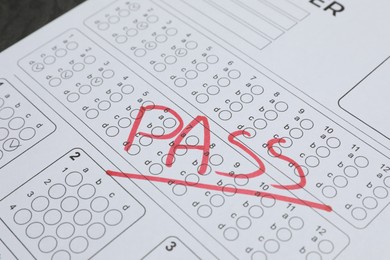Photo of Word Pass written with red marker on answer sheet, closeup. Student passing exam