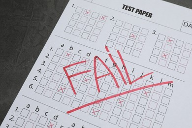 Photo of Answer sheet with word Fail on gray textured table, closeup. Student passing exam