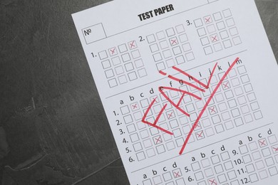 Photo of Answer sheet with word Fail on gray textured table, top view. Student passing exam