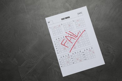 Photo of Student passing exam. Answer sheet with word Fail on gray textured table, top view. Space for text