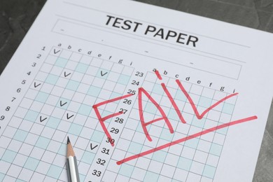 Photo of Answer sheet with word Fail and pencil on gray table, closeup. Student passing exam