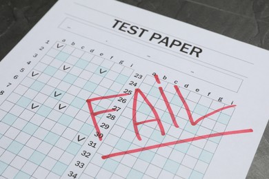 Photo of Answer sheet with word Fail on gray table, closeup. Student passing exam