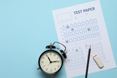 Photo of Student passing exam. Answer sheet, alarm clock, pencil and eraser on light blue background, flat lay. Space for text