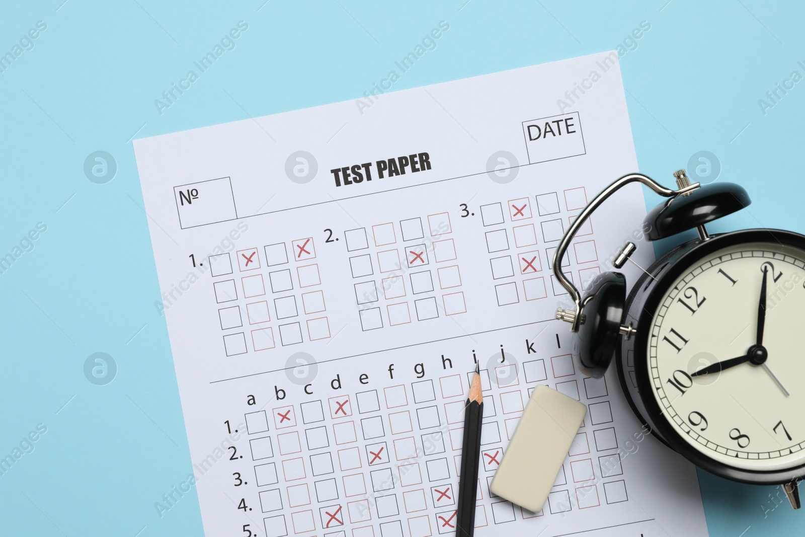 Answer sheet, alarm clock, pencil and eraser on light blue background, flat lay. Student passing exam Photo of Answer sheet, alarm clock, pencil and eraser on light blue background, flat lay. Student passing exam