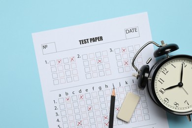 Photo of Answer sheet, alarm clock, pencil and eraser on light blue background, flat lay. Student passing exam