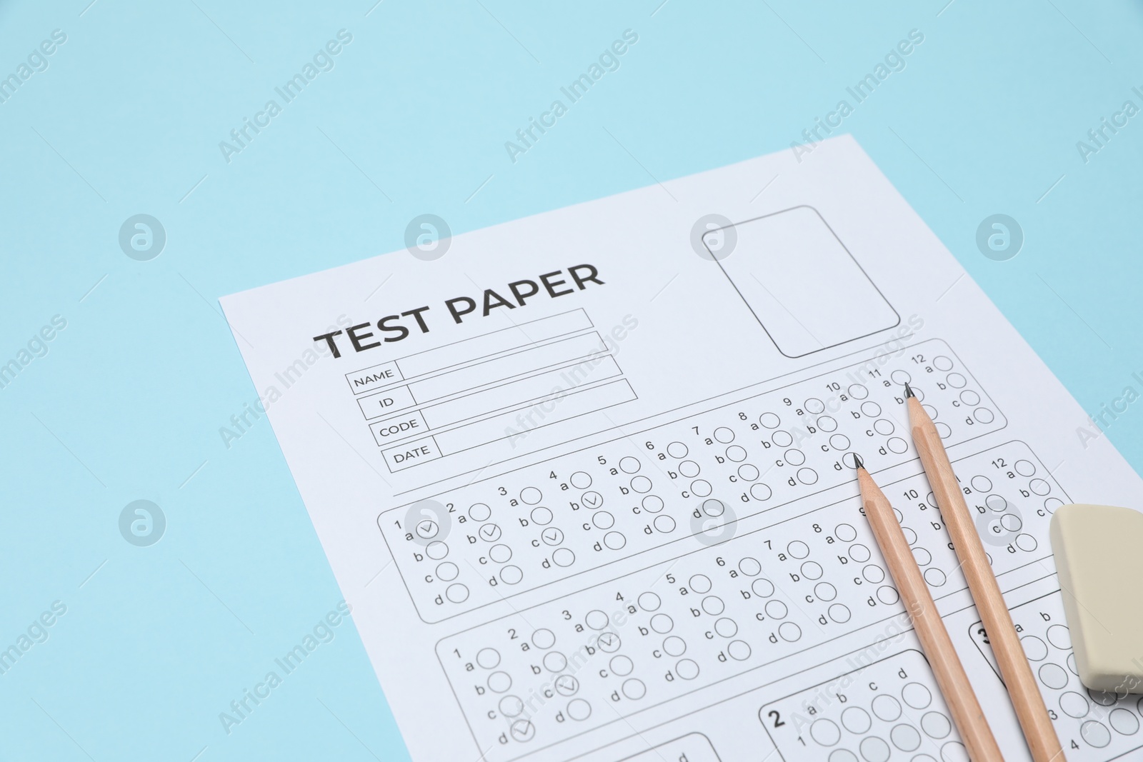 Answer sheet, pencils and eraser on light blue background, closeup. Student passing exam Photo of Answer sheet, pencils and eraser on light blue background, closeup. Student passing exam