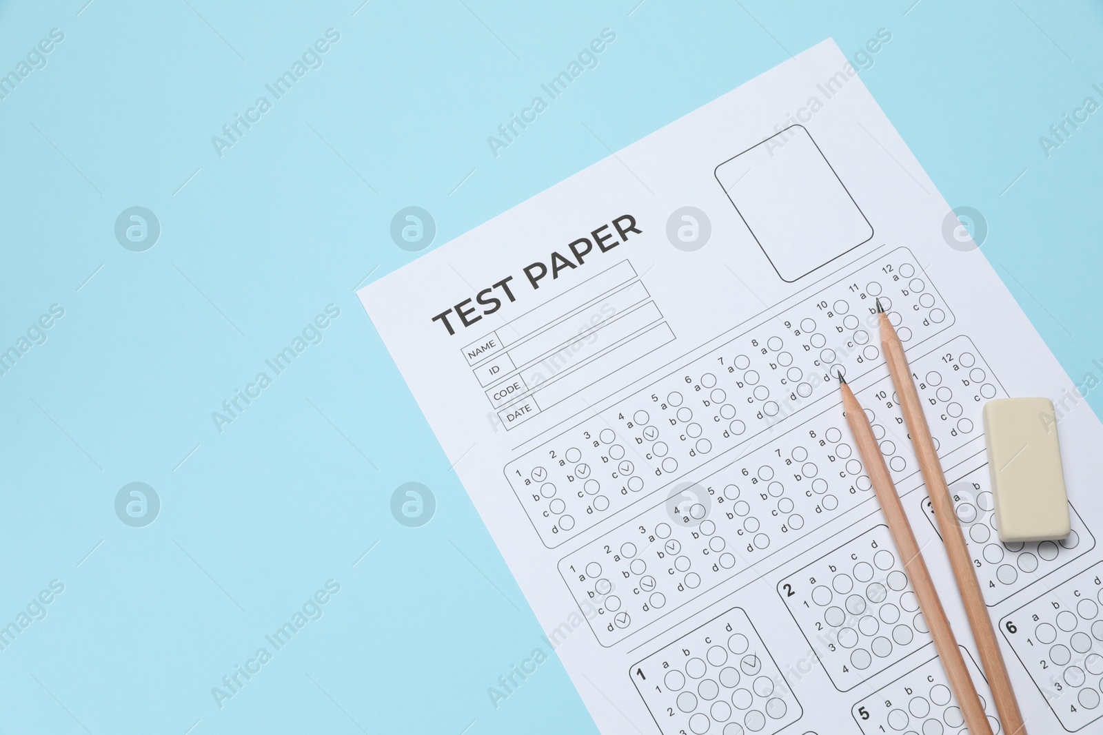 Answer sheet, pencils and eraser on light blue background, above view. Student passing exam Photo of Answer sheet, pencils and eraser on light blue background, above view. Student passing exam