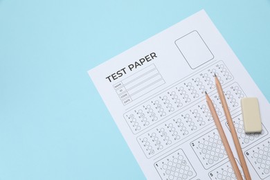 Photo of Answer sheet, pencils and eraser on light blue background, above view. Student passing exam
