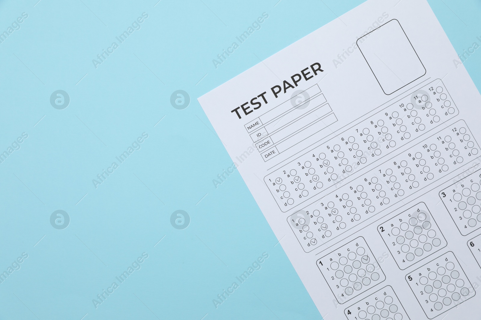 Student passing exam. Answer sheet on light blue background, top view. Space for text Photo of Student passing exam. Answer sheet on light blue background, top view. Space for text
