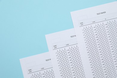 Photo of Answer sheets on light blue background, flat lay. Student passing exam