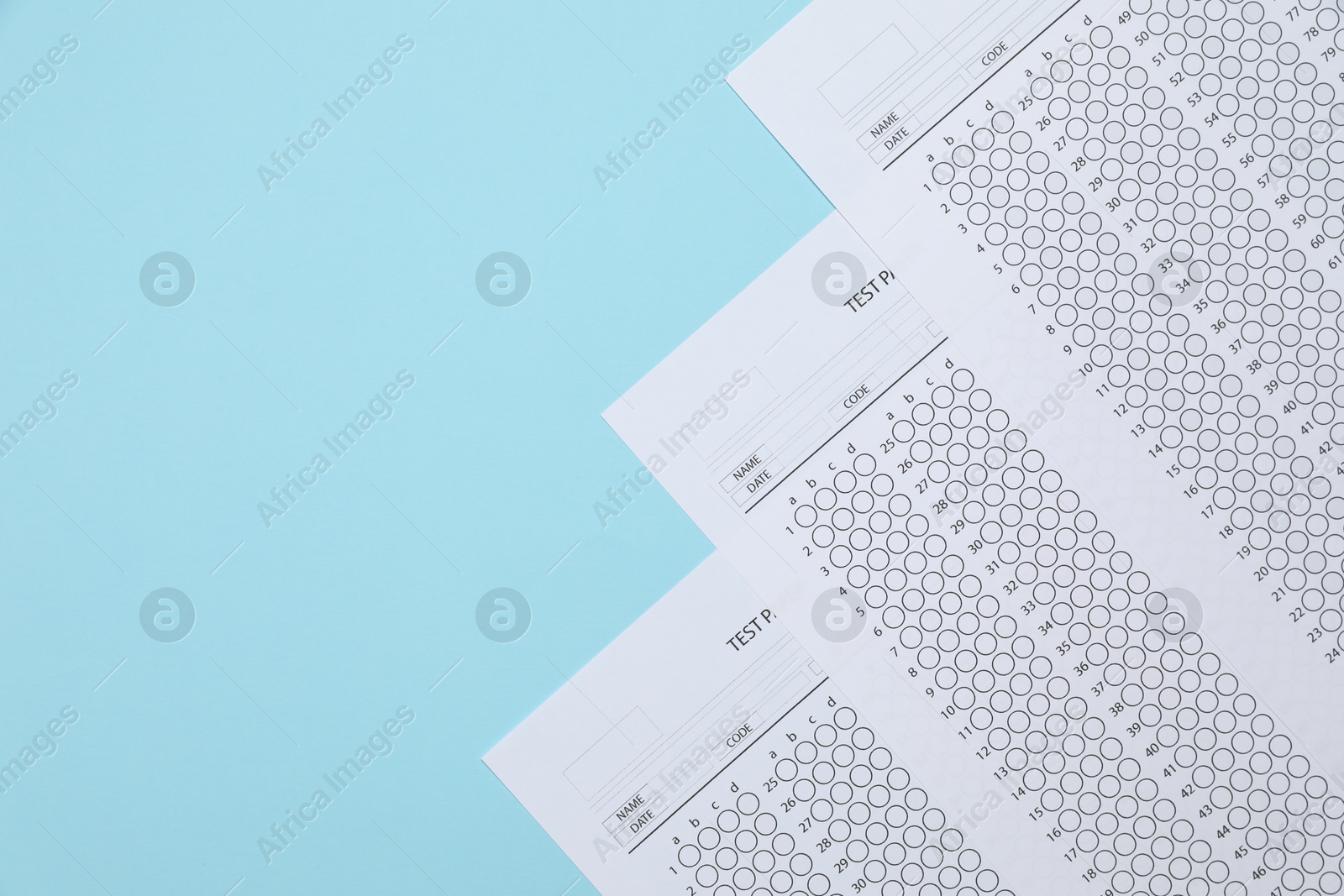 Student passing exam. Answer sheets on light blue background, flat lay. Space for text Photo of Student passing exam. Answer sheets on light blue background, flat lay. Space for text