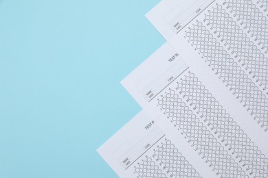 Photo of Student passing exam. Answer sheets on light blue background, flat lay. Space for text