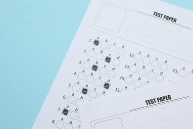 Photo of Answer sheets on light blue background, flat lay. Student passing exam