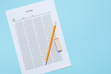 Photo of Student passing exam. Answer sheet, eraser and pencil on light blue background, top view. Space for text