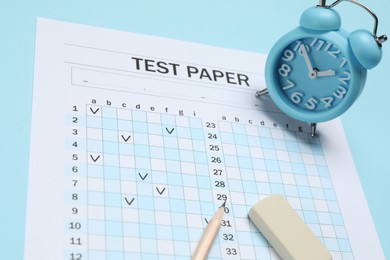 Photo of Answer sheet, alarm clock, pencil and eraser on light blue background, closeup. Student passing exam
