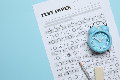 Photo of Answer sheet, alarm clock, pencil and eraser on light blue background, flat lay. Student passing exam