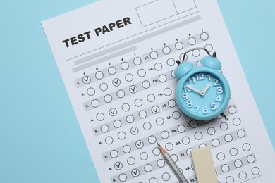 Photo of Answer sheet, alarm clock, pencil and eraser on light blue background, flat lay. Student passing exam
