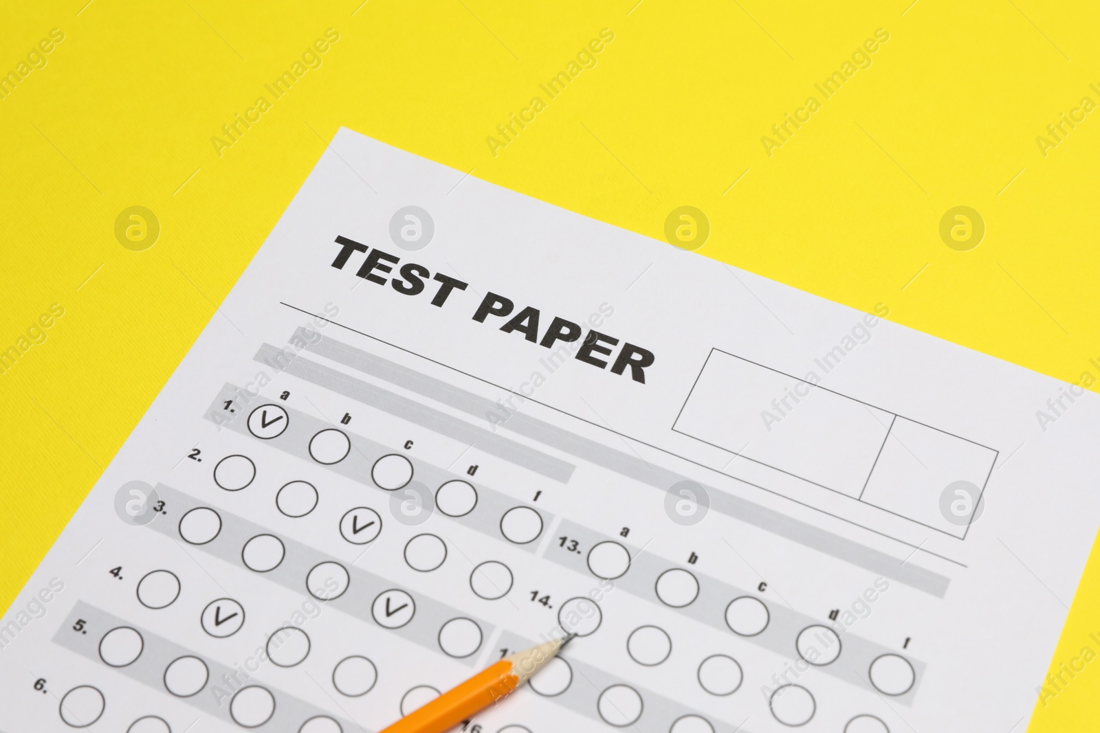 Photo of Answer sheet and pencil on yellow background, closeup. Student passing exam