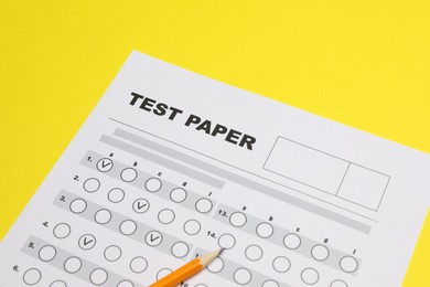 Photo of Answer sheet and pencil on yellow background, closeup. Student passing exam