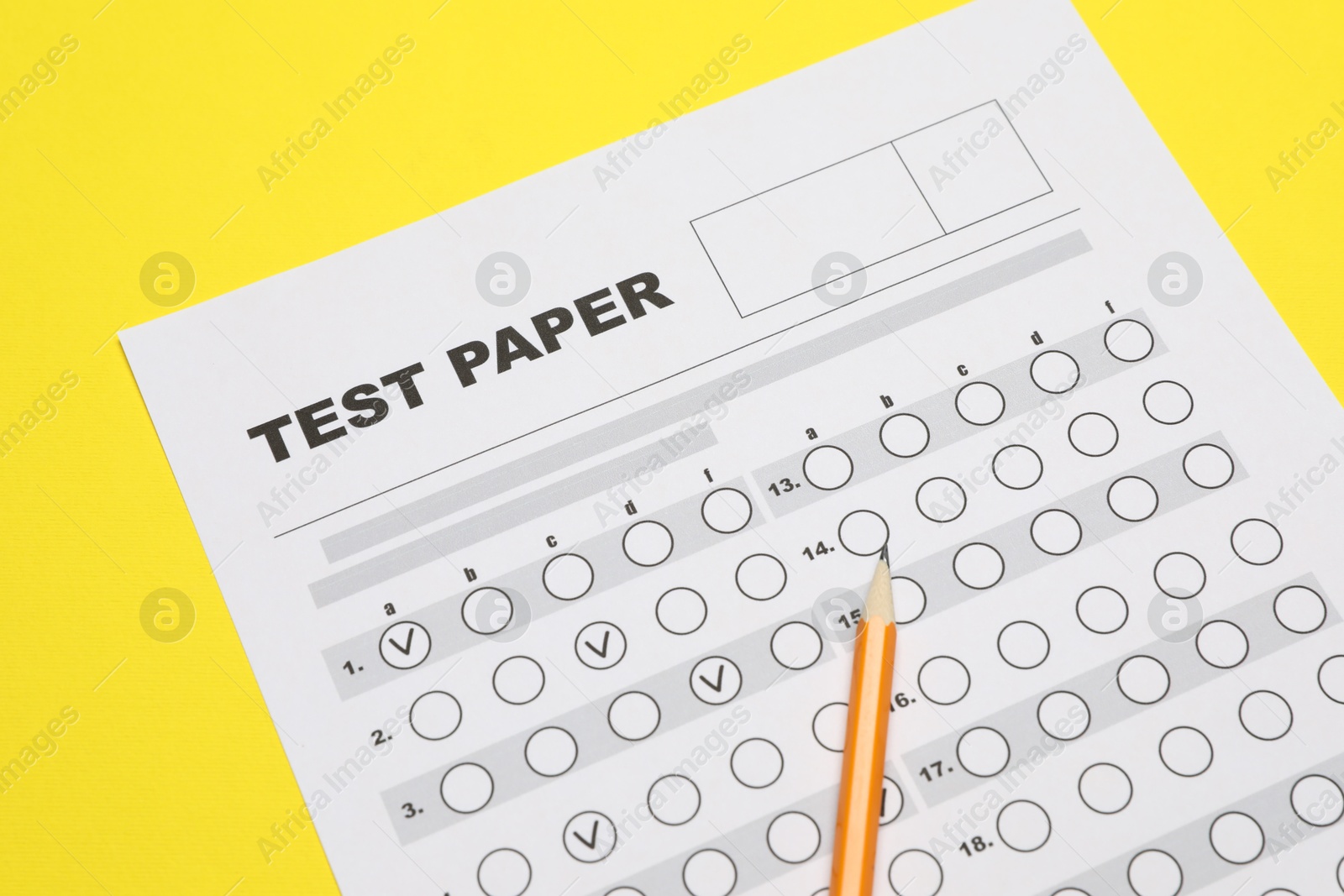 Photo of Answer sheet and pencil on yellow background, closeup. Student passing exam
