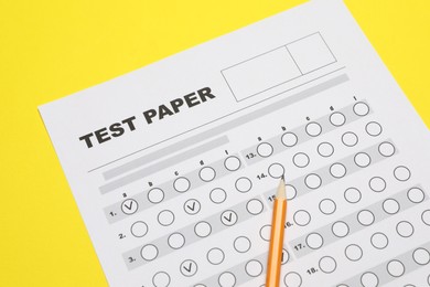 Photo of Answer sheet and pencil on yellow background, closeup. Student passing exam
