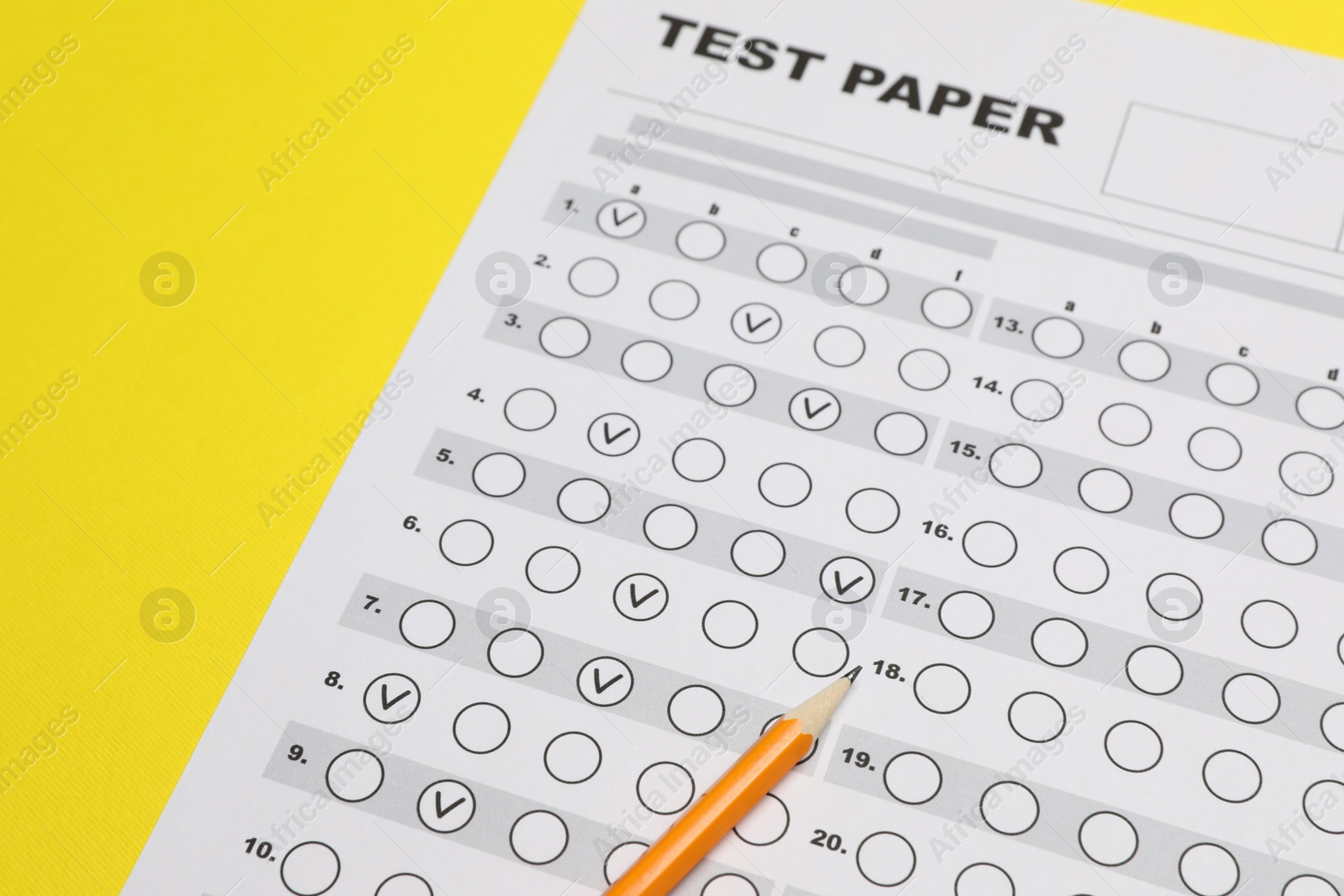 Photo of Answer sheet and pencil on yellow background, closeup. Student passing exam