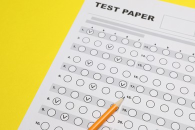 Photo of Answer sheet and pencil on yellow background, closeup. Student passing exam