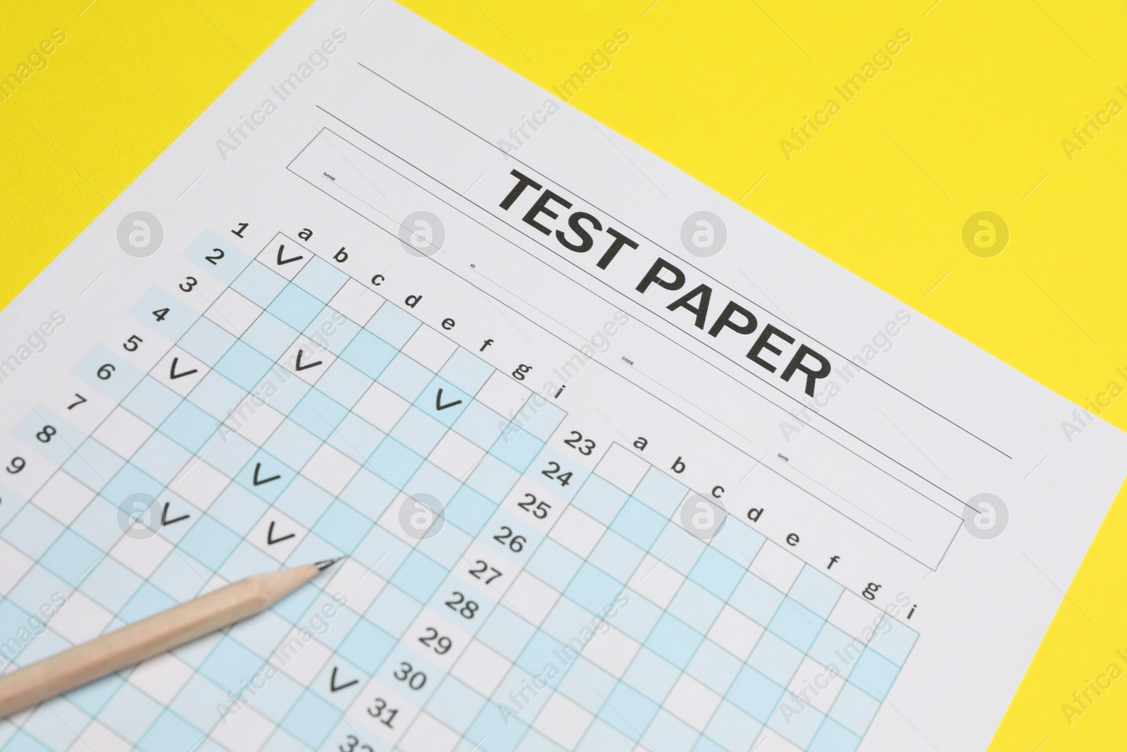 Photo of Answer sheet and pencil on yellow background, closeup. Student passing exam