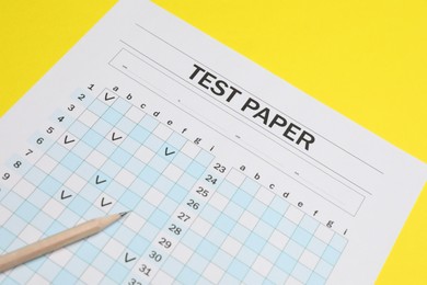 Photo of Answer sheet and pencil on yellow background, closeup. Student passing exam