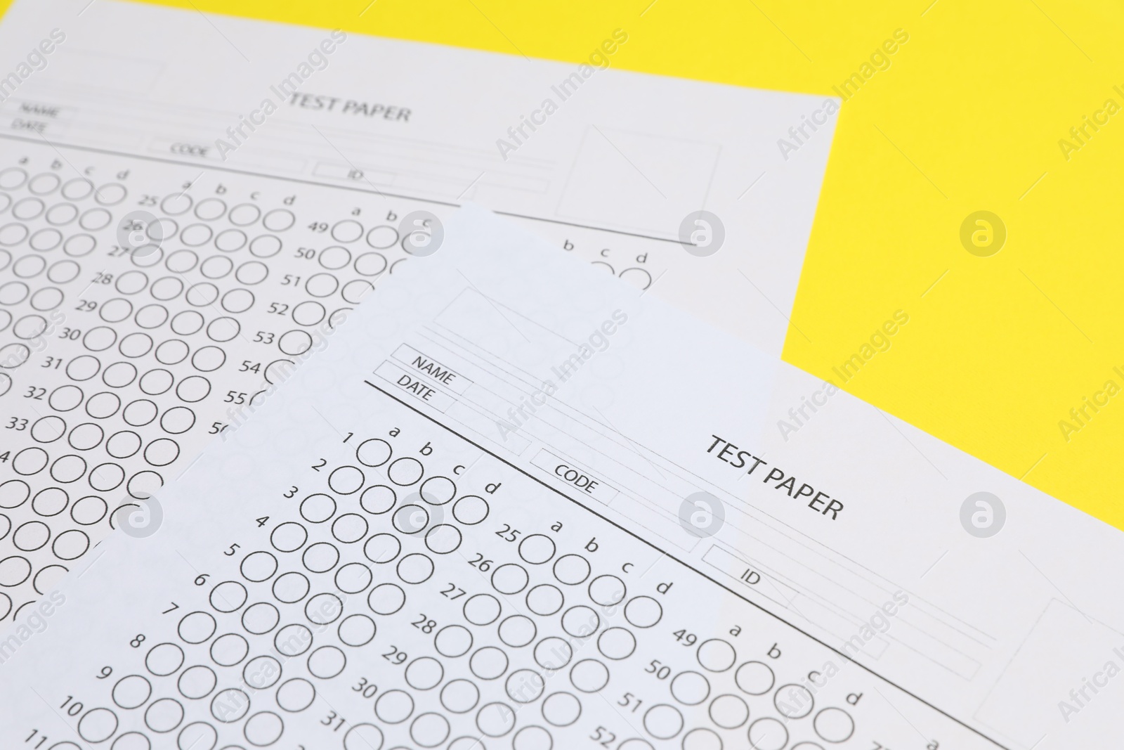 Photo of Answer sheets on yellow background, closeup. Student passing exam