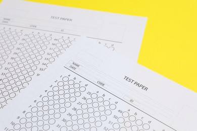 Photo of Answer sheets on yellow background, closeup. Student passing exam