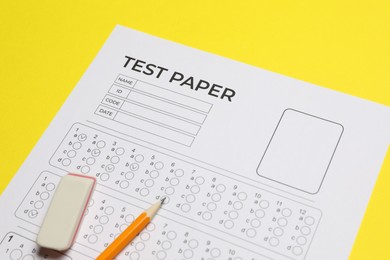 Photo of Answer sheet, pencil and eraser on yellow background, closeup. Student passing exam